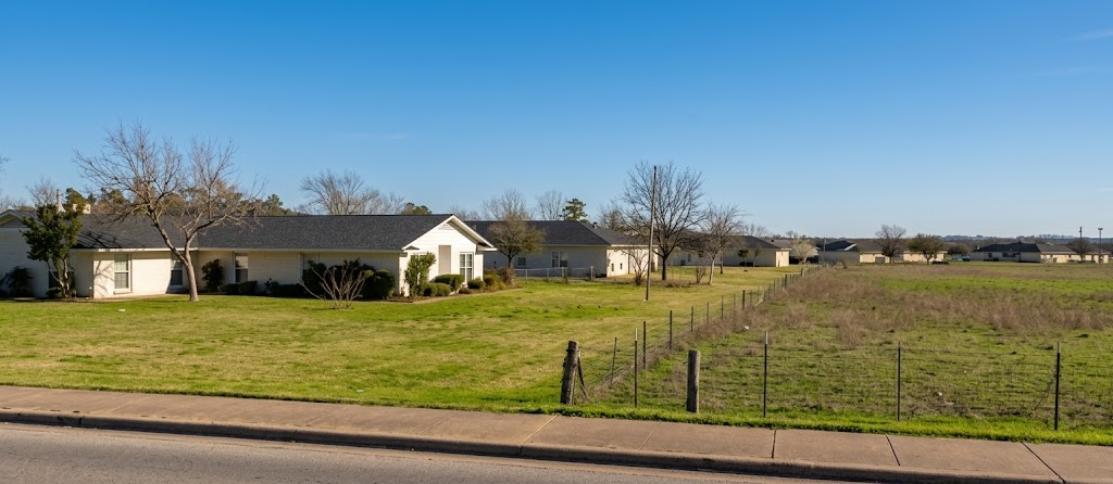 A peaceful Serenity House residential home with open lawn under a clear blue sky
